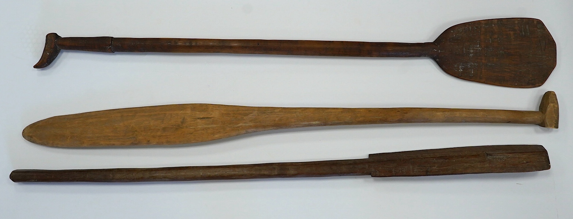 Two tribal carved wood paddles and an ironwood club, longest 104cm. Condition - poor to fair, one paddle missing part of the grip, splits to the wood, etc.